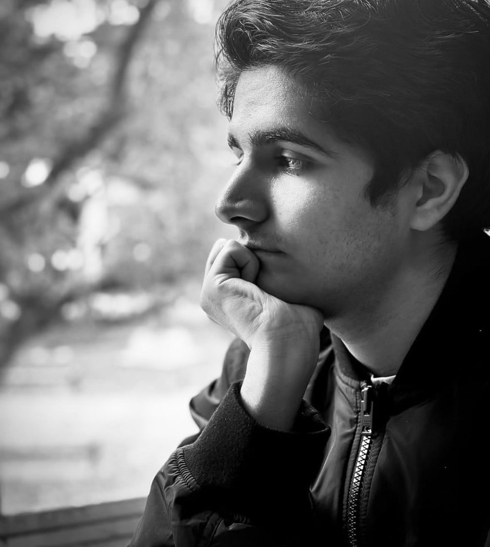 Aniket S sitting outdoors at night, lit by a single warm lamp