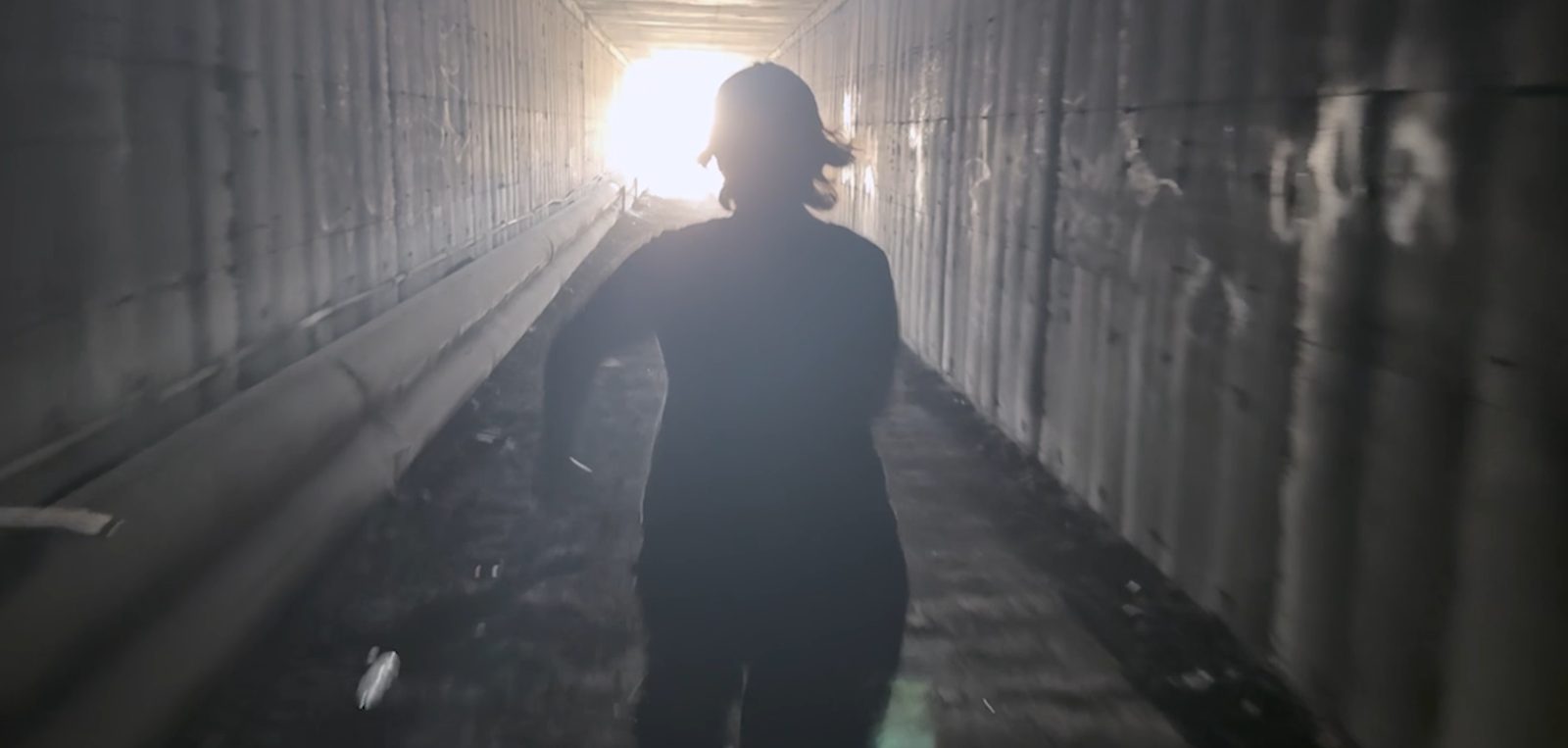 A man alone in a dimly lit concrete tunnel, still frame from the short film IrRATional